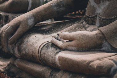 Buda heykelinin meditasyondaki elinin sinematik fotoğrafı zihin ve beden, farkındalık ve sağIık arasındaki uyumu göstermek için poz veriyor.