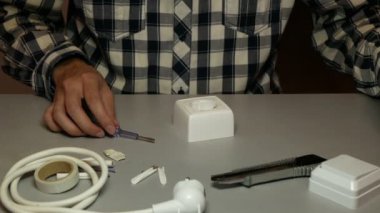 Elektrikçi beyaz elektrik prizini söker. Erkek ellerine yakından bak. 4k görüntü.