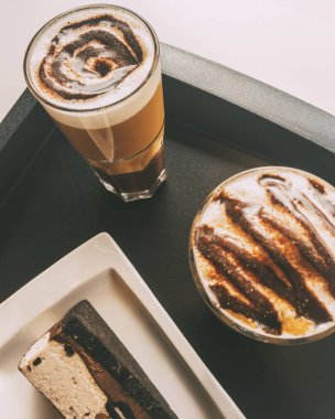 Çikolatalı ve karamel kremalı iki Latte Macchiato çikolatalı pasta ve kurabiyenin yanında içmeye hazır.