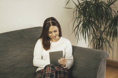 Evde tabletini kullanan genç bir kadın.