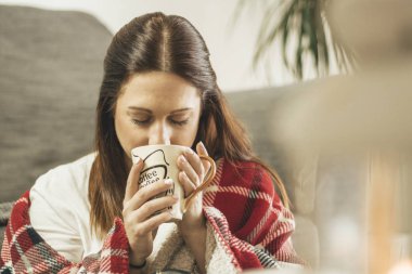 Genç bayan evde rahatlamış bir fincan kahvenin tadını çıkarıyor.