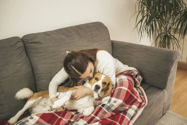 Relaxado jovem mulher no sofá em casa, com seu cão — Fotografia de Stock