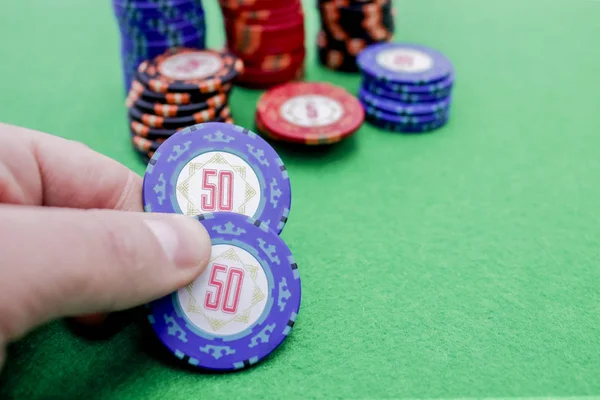 Bir yığın fişin yanında iki tane mavi poker fişi var.