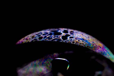 Çarpıcı renklere sahip bir sabun köpüğünün makro fotoğrafı ve gezegen benzeri bir görünüm, seçici odak