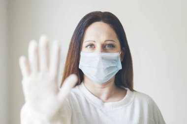Genç kahverengi saçlı kadın tıbbi maske ve lateks eldivenlerle korunuyor. COVID-19, koronavirüs, seçici odaklanma.