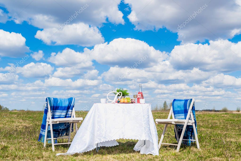 A table with fruits, sweets and wine for a date for two against a blue sky