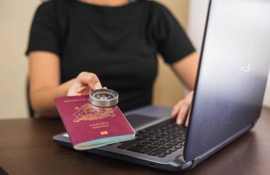  Latin bir adam masasının önünde elinde gri bir dizüstü bilgisayarla Şili kırmızı pasaportu ve pusulası var.