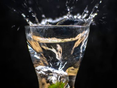 Suya düşen kireç. Siyah arkaplan ve zıt su sıçraması fotoğrafları. Meyvenin su üzerindeki keskin etkisi