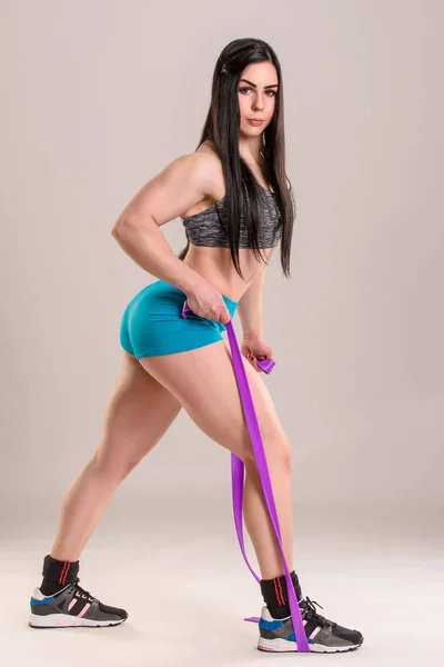 Bodybuildermädchen Macht Übung Mit Lila Fitnessgummi Auf Grauem Hintergrund — Stockfoto