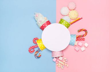 Pastel pembe ve mavi arka plan üzerinde üstten görünüm şeker, lokum, lolipop, pamuk şeker. En az stili