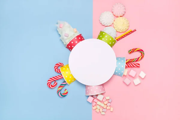 Vista superior de los dulces, malvaviscos, piruletas, algodón de azúcar sobre un fondo azul pastel y rosa. Estilo mínimo —  Fotos de Stock