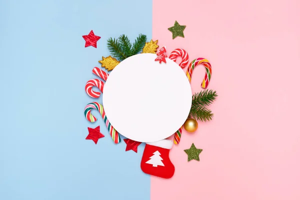 Üstten Görünüm Noel süslemeleri, tatlılar, şeker kamışı, çam dalları, pastel mavi ve pembe arka plan üzerinde. Noel kartları kavramı. 