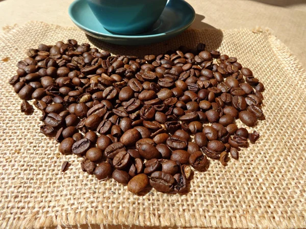 Кофейные зерна в форме сердца на фоне мешковины — стоковое фото