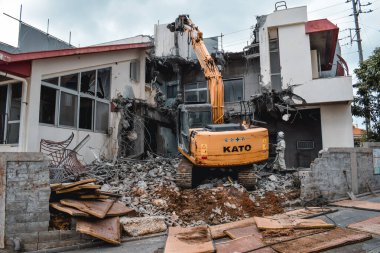 Sarı kazıcı Naha Okinawa Japonya 'daki bir tayfundan sonra bir evin kalıntılarını temizliyor.