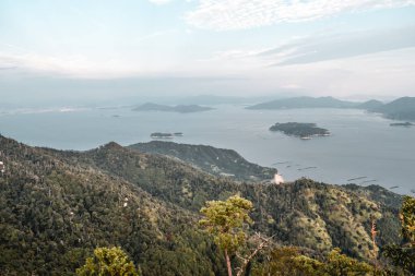 Japonya 'nın Hiroşima adasındaki Miyajima adasındaki Misen Dağı' ndan güzel ormanlar, bulutlu gökyüzü ve inci çiftlikleri.