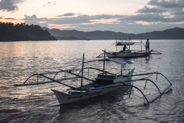 Geleneksel Filipinli balıkçılar, Filipinler 'deki El Nido Palawan' da gün batımında tekneleriyle evlerine dönüyorlar.