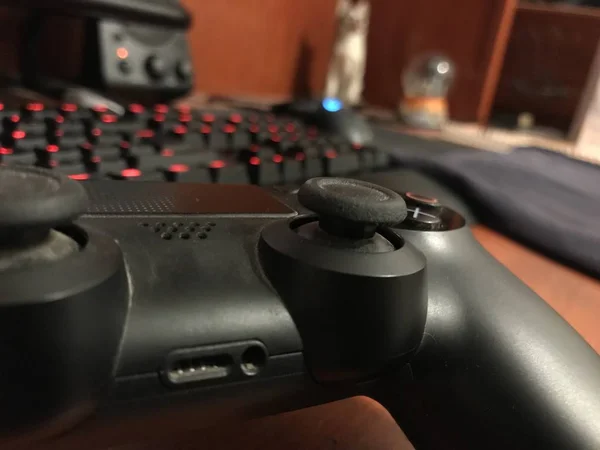 Puebla, Mexico; 15 september 2019: Zwarte gaming controller over een houten bureau met een mechanisch toetsenbord — Stockfoto