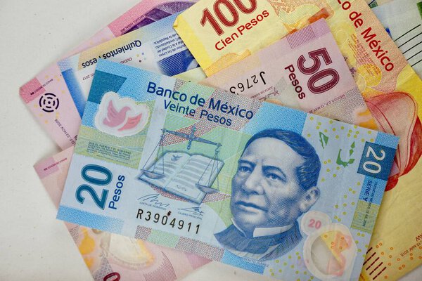 Мексиканские песо-купюры распространились случайно по плоской поверхности.
