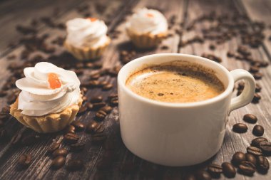 Kahverengi kremalı ve meyveli bir fincan kahve ve kek sepeti..