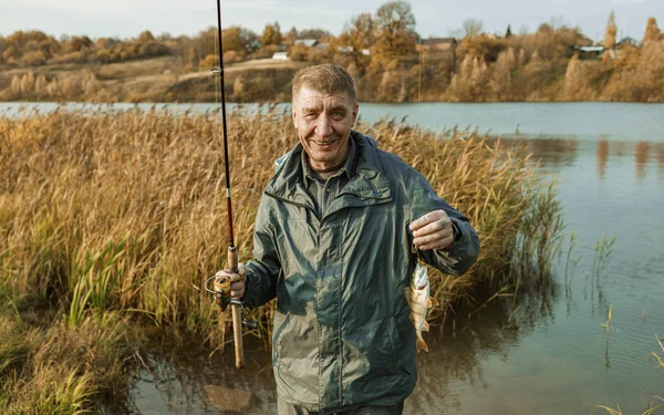 Starszy rybak z rudymi włosami złapał dobrą rybę okonia. — Zdjęcie stockowe