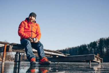 Yalnız bir gezgin buzun üzerinde duruyor ve termostan çay içiyor..