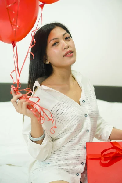 Bonita asiática dama en cama sosteniendo rojo globo y rojo caja valentine concepto — Foto de Stock