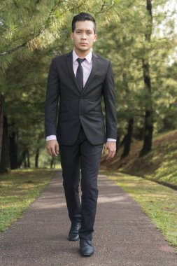 Genç Asyalı Malay Adam parkta takım elbise giymiş.