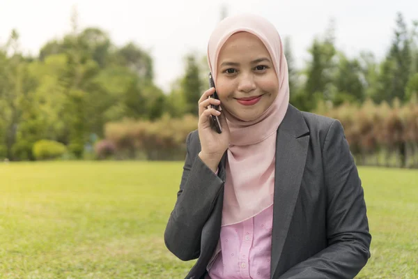 Asiático mulheres de negócios vestindo hijab sorrindo ao usar o telefone móvel — Fotografia de Stock