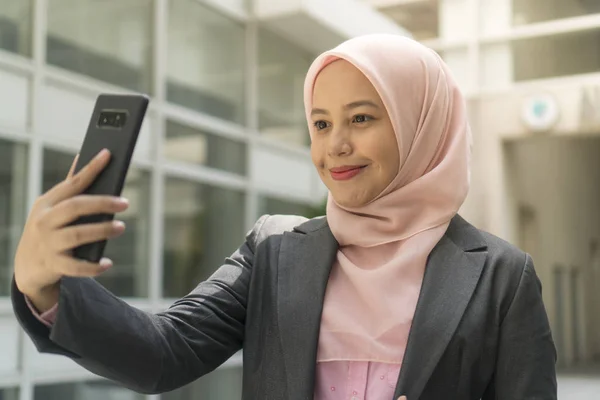 Asian Business Women wearing hijab smiling while using mobile phone