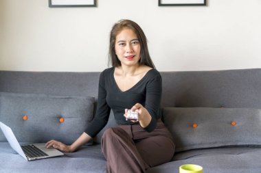 Asyalı Malezyalı kız kanepede yalnız oturuyor.