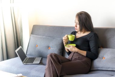 Asyalı Malezyalı kız kanepede yalnız oturuyor.