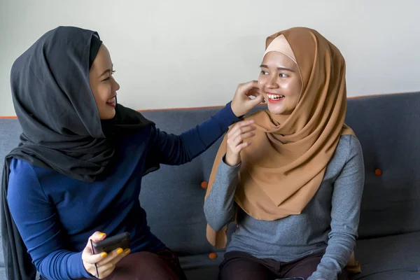 Two Malay friends wearing hijab at the sofa