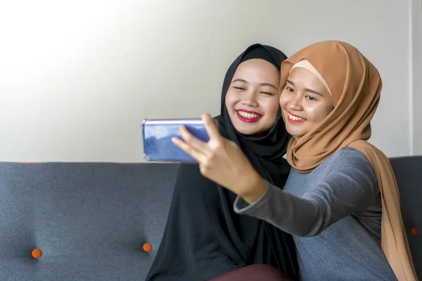 Dois amigos malaios vestindo hijab no sofá — Fotografia de Stock