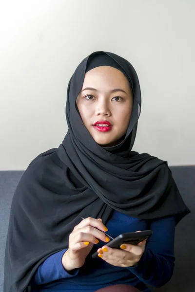 Ásia malaio menina vestindo hijab sentado no o sofá — Fotografia de Stock