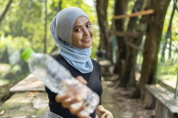 Malezyalı Müslüman kadın tesettürlü açık havada dinleniyor ve su içiyor — Stok fotoğraf