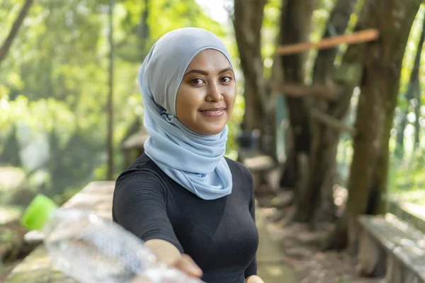 Malezyalı Müslüman kadın tesettürlü açık havada dinleniyor ve su içiyor