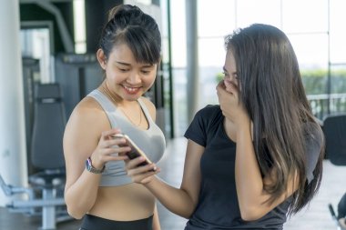 Sağlıklı kavram, spor salonunda akıllı telefon kullanan tatlı Asyalı kız.