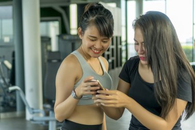 Sağlıklı kavram, spor salonunda akıllı telefon kullanan tatlı Asyalı kız.