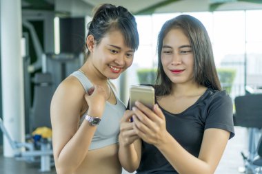 Sağlıklı kavram, spor salonunda akıllı telefon kullanan tatlı Asyalı kız.