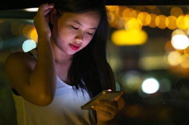 Yaşam tarzı konsepti, güzel Asyalı kız gece akıllı telefon kullanıyor.