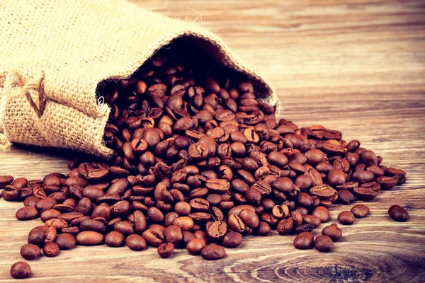 The sack of coffee beans on wooden background — Stock Photo, Image