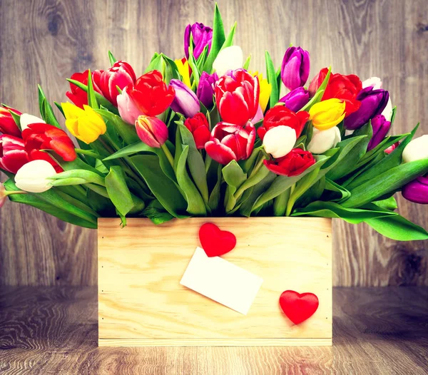 Tulipanes en la caja sobre fondo de madera.Imagen tonificada . — Foto de Stock