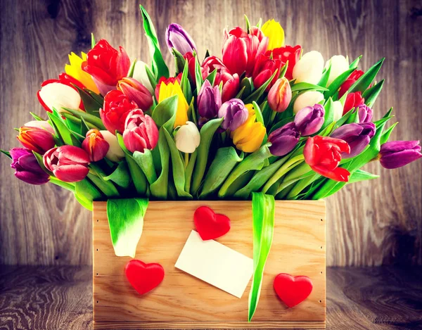 Tulips in the box on wooden background.Toned image. — Stock Photo, Image