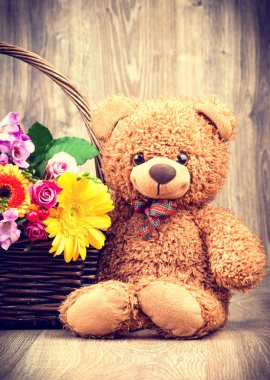 Çiçek demet ve ahşap arka plan üzerinde bir oyuncak ayı