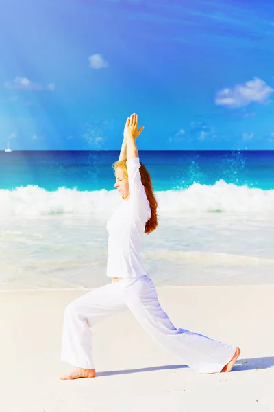 Jeune femme pratique le yoga sur la plage — Photo