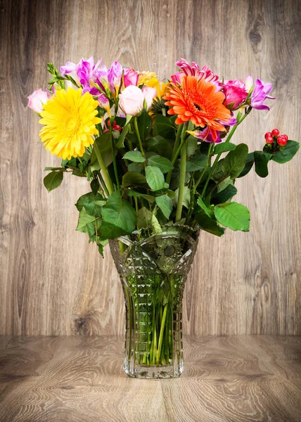 Mixed beautiful flowers in the vase on wooden background — Stock Photo, Image