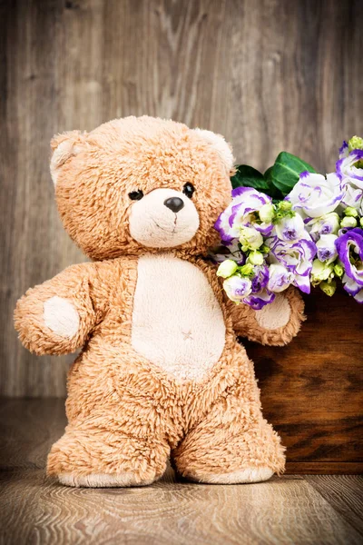 Bunch of flowers and a teddy bear on wooden background — Stock Photo, Image