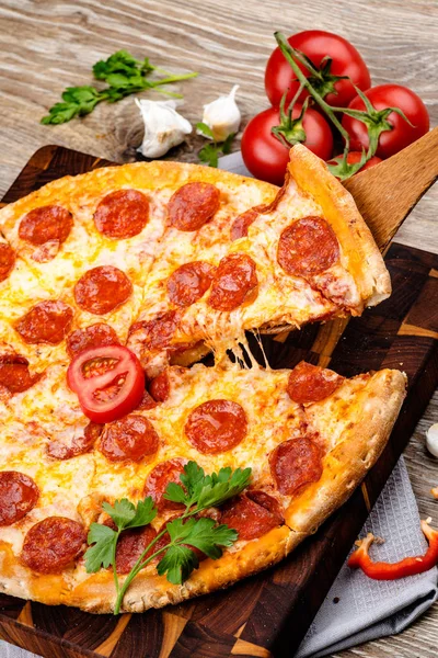 Foto de una pizza caliente sobre fondo de madera. Imagen tonificada —  Fotos de Stock