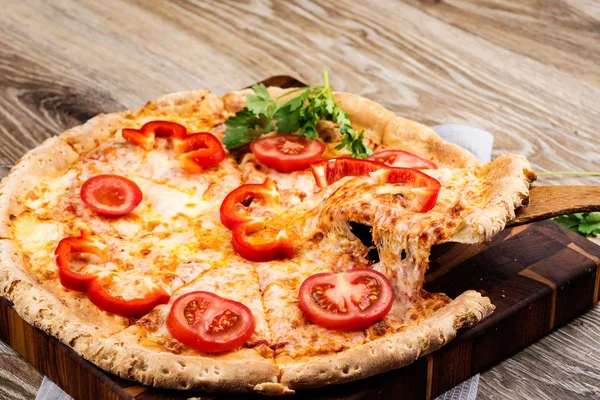 Foto de una pizza caliente sobre fondo de madera. Imagen tonificada —  Fotos de Stock