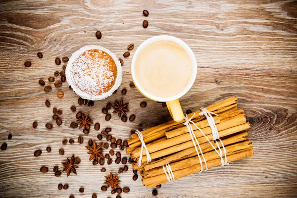 Cup of coffee, a cake and cinnamon sticks on wooden background — Stock Photo, Image
